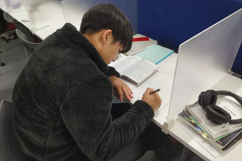 칸막이 책상에서 공부하는 기숙사생