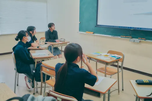 교실에서 책상을 사이에 두고 상담하는 학생과 교원