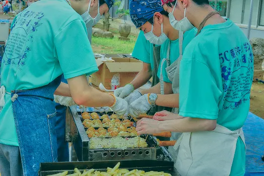 같은 티셔츠를 입고 철판에서 음식을 만드는 학생들
