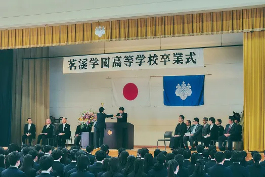'茗溪学園高等学校卒業式' 현수막이 걸린 강당에서 열리는 졸업식