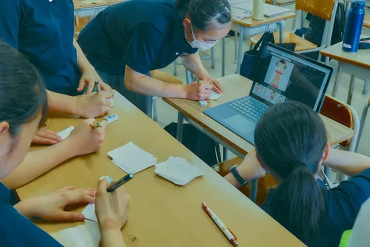교실에서 노트북과 메모지를 놓고 작업하는 학생들과 교원
