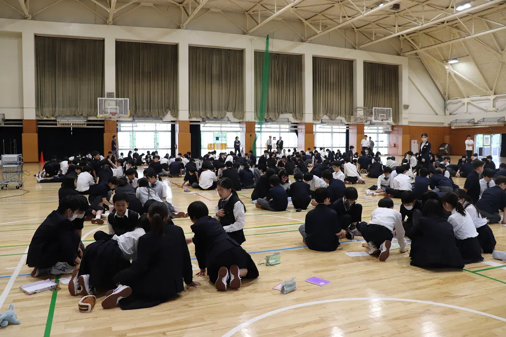 체육관 바닥에 모둠별로 둘러앉아 카드 게임을 하는 중학교 1학년 학생들