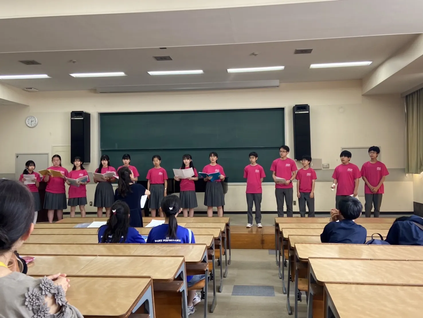 분홍 티셔츠를 맞춰 입고 강의실 칠판 앞에 한 줄로 서서 노래하는 합창부