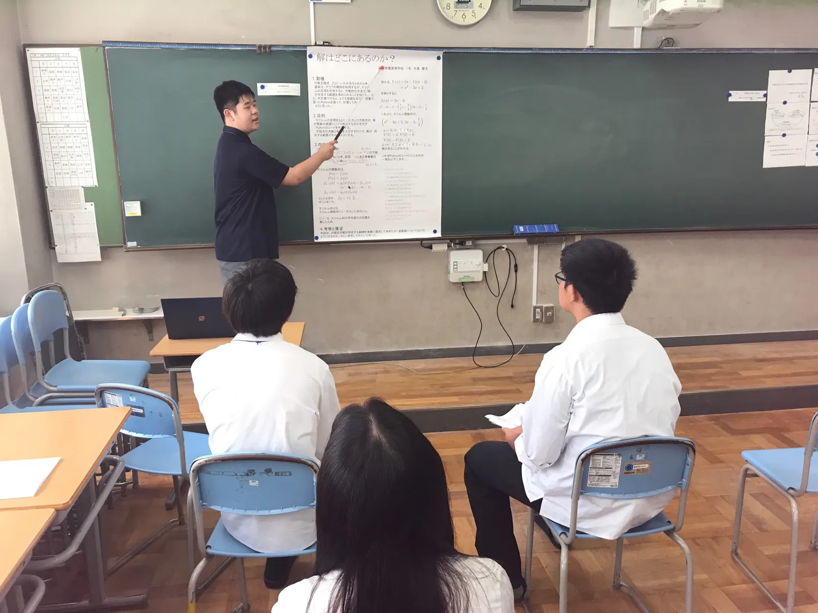 칠판에 붙인 연구 포스터 '해는 어디에 있는가'를 지시봉으로 가리키며 발표하는 수학반 학생