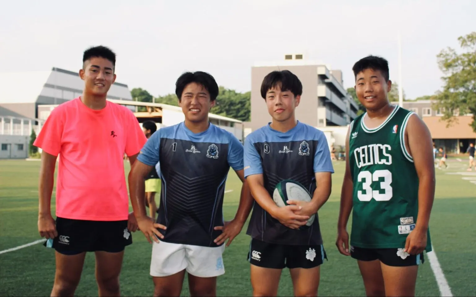 운동장에 나란히 서서 웃는 R 학생과 럭비부원 세 명