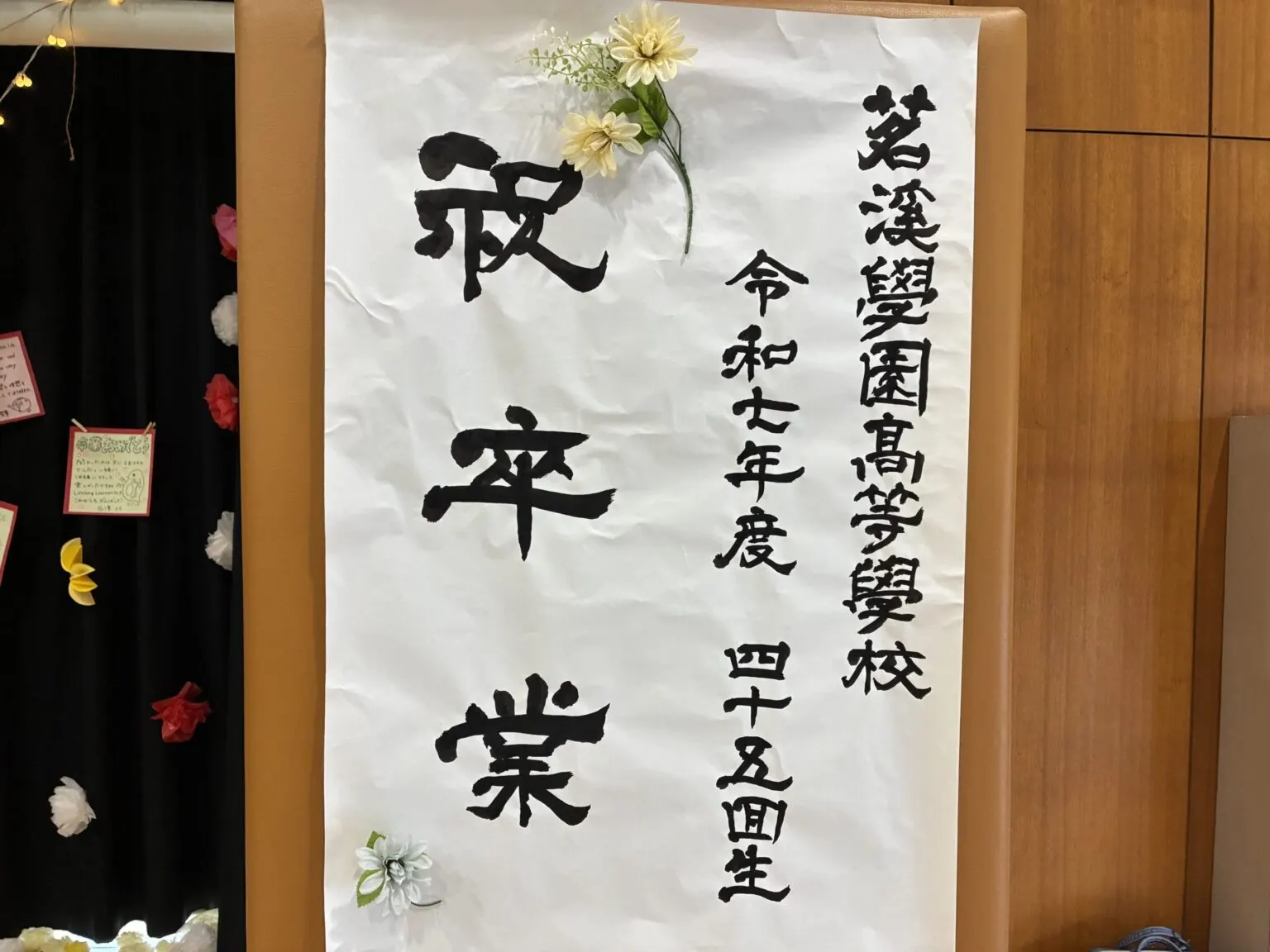 조화로 꾸민 '축 졸업' 붓글씨 족자. 메이케이가쿠엔 고등학교 레이와 7년도 45기생이라고 적혀 있다