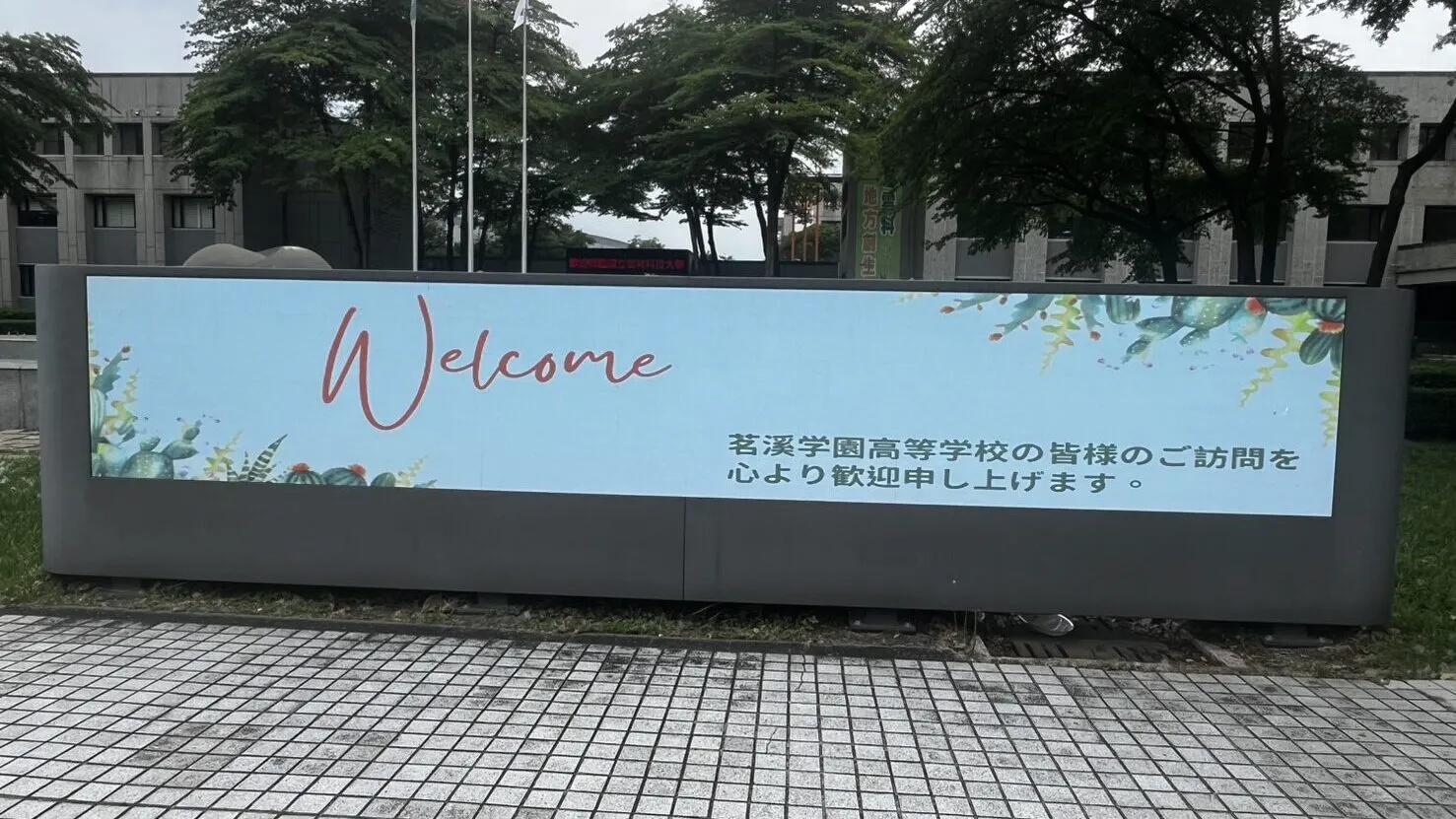캠퍼스 앞 전광판에 Welcome과 함께 메이케이가쿠엔 고등학교 방문을 진심으로 환영한다는 일본어 문구가 떠 있는 모습