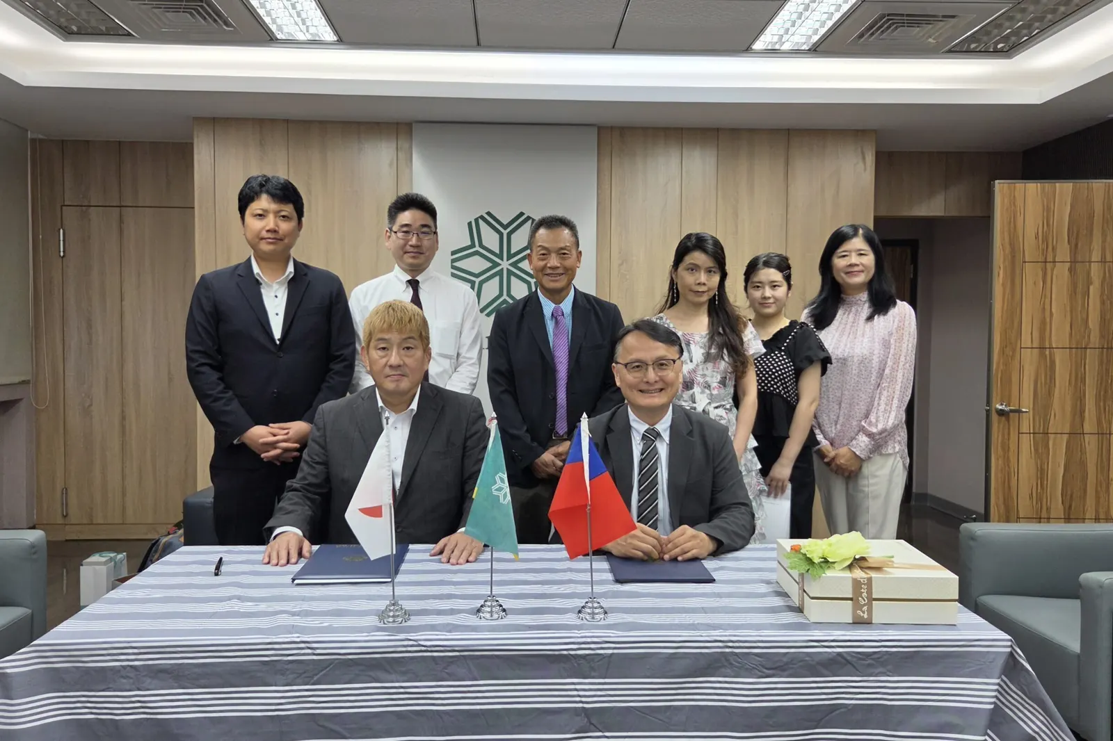 협정식 탁자에 앉은 두 학교 대표와 뒤에 선 양교 관계자들의 기념사진