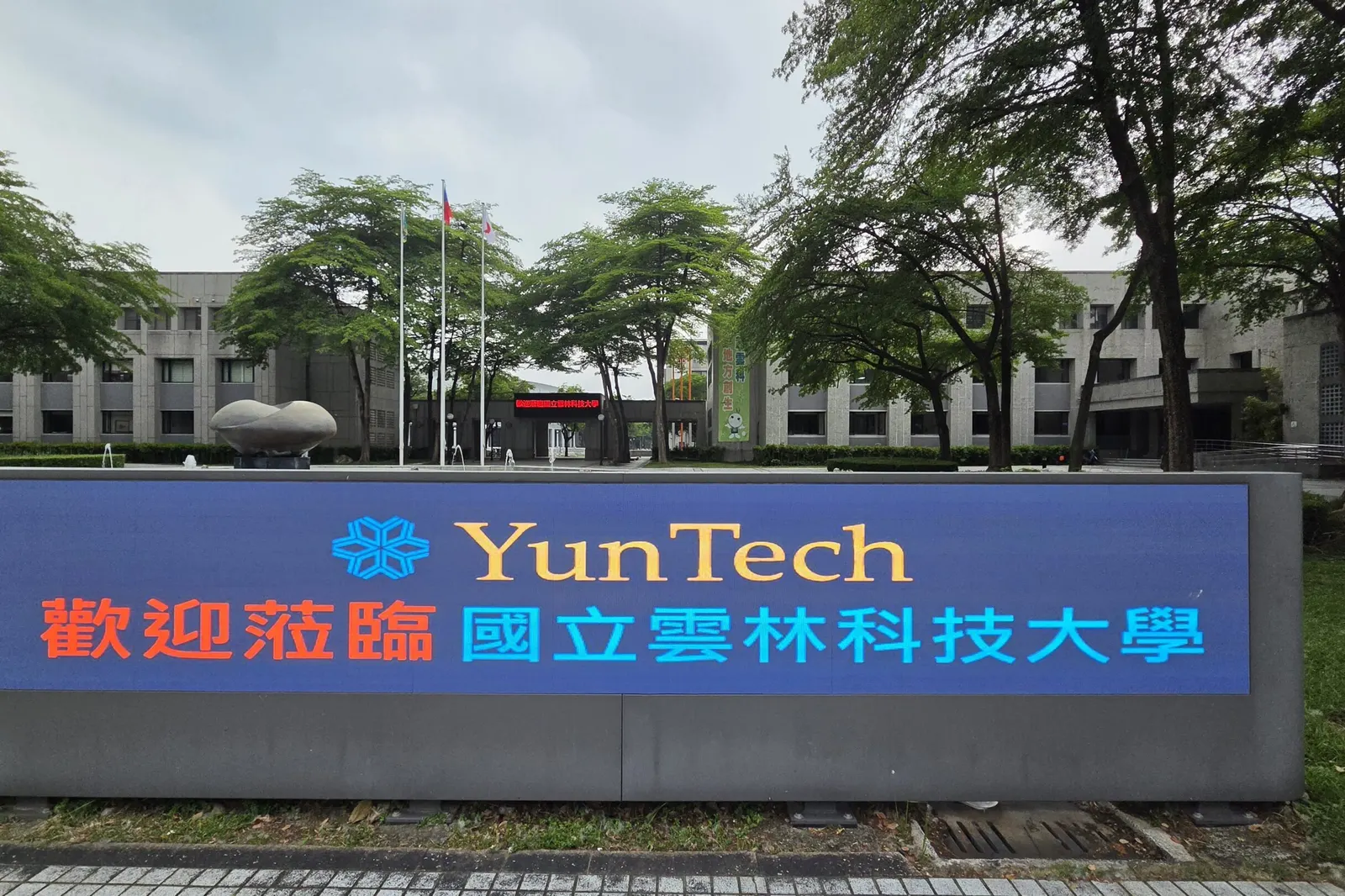 YunTech 로고와 국립윈린과기대학 환영 문구가 나오는 전광판 너머로 보이는 캠퍼스 건물과 나무들