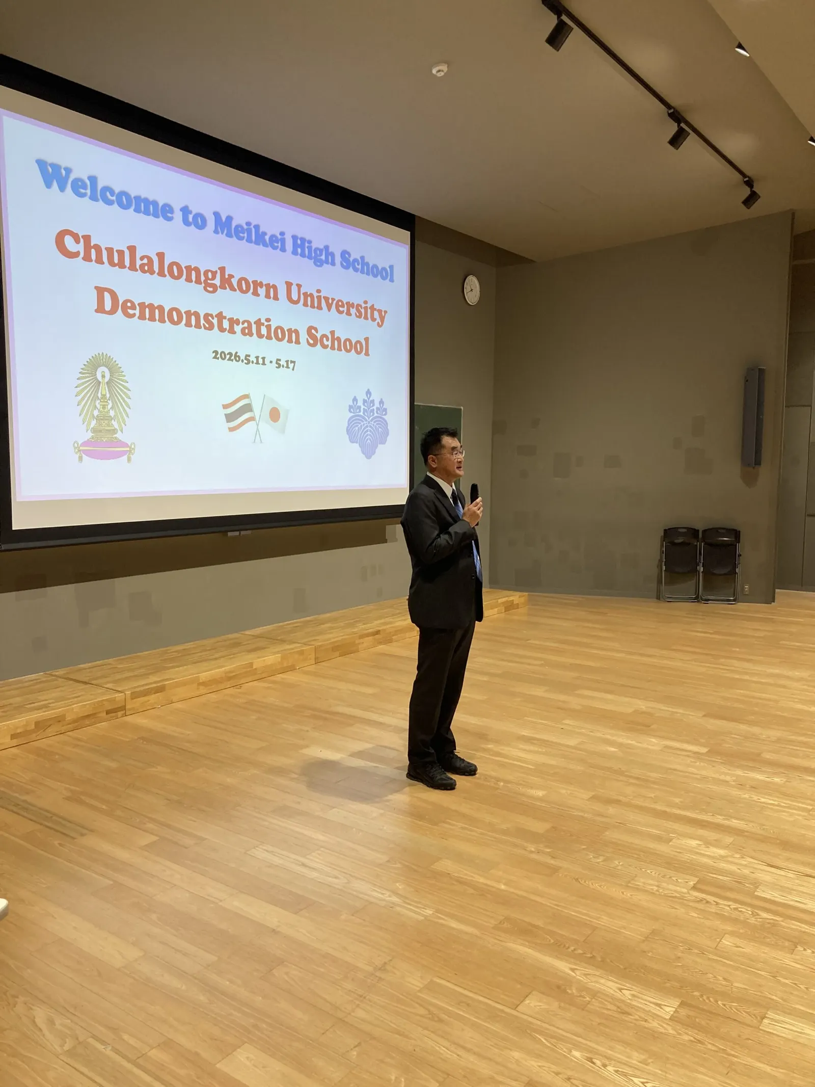Welcome to Meikei High School, Chulalongkorn University Demonstration School 2026.5.11~5.17 화면 앞에서 마이크를 들고 환영 인사를 하는 부교장