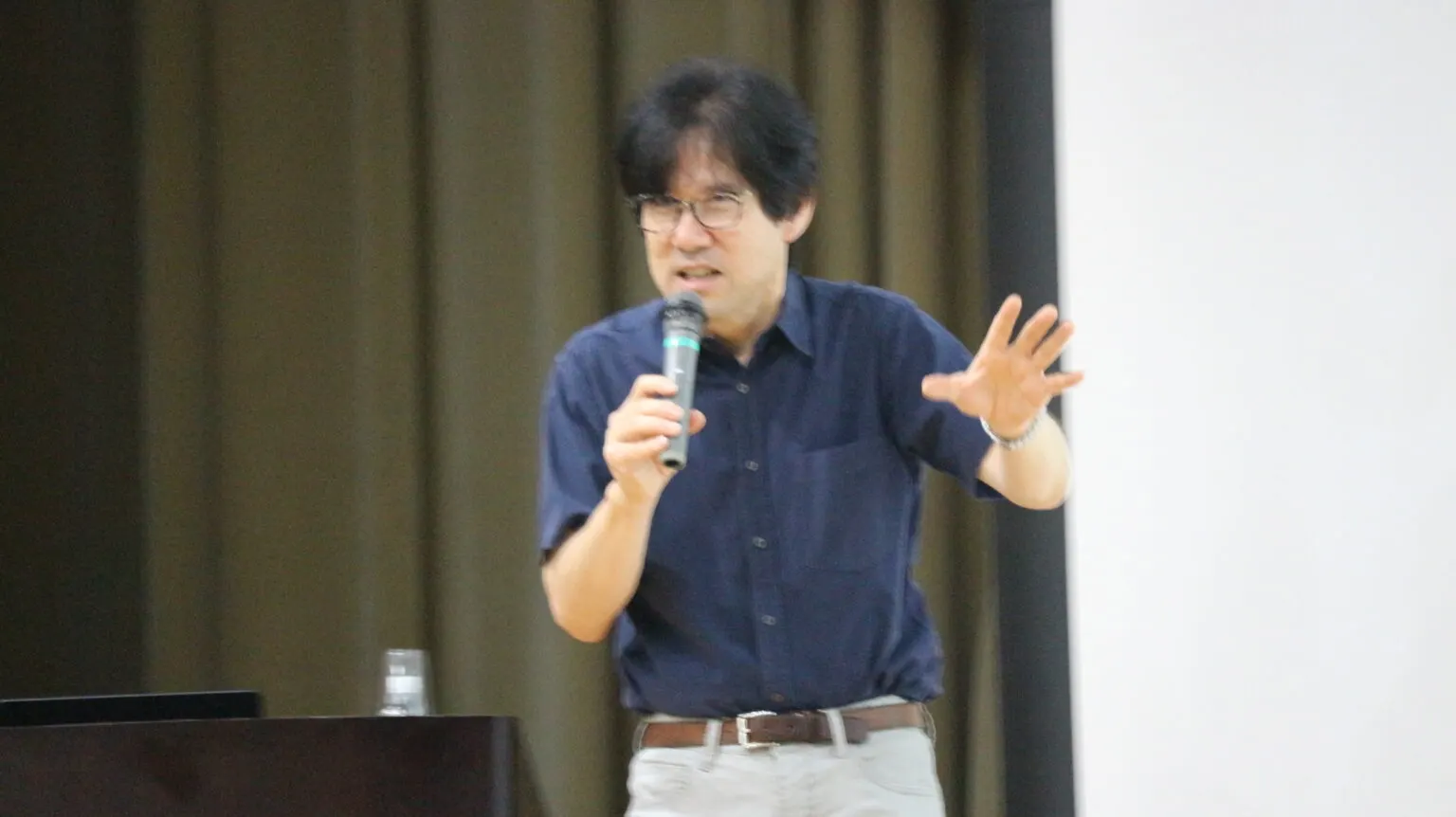 특별 강연에서 마이크를 들고 손짓하며 설명하는 강연자