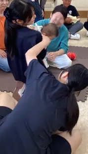 보호자 곁에서 아기를 조심스럽게 안아 올리는 학생