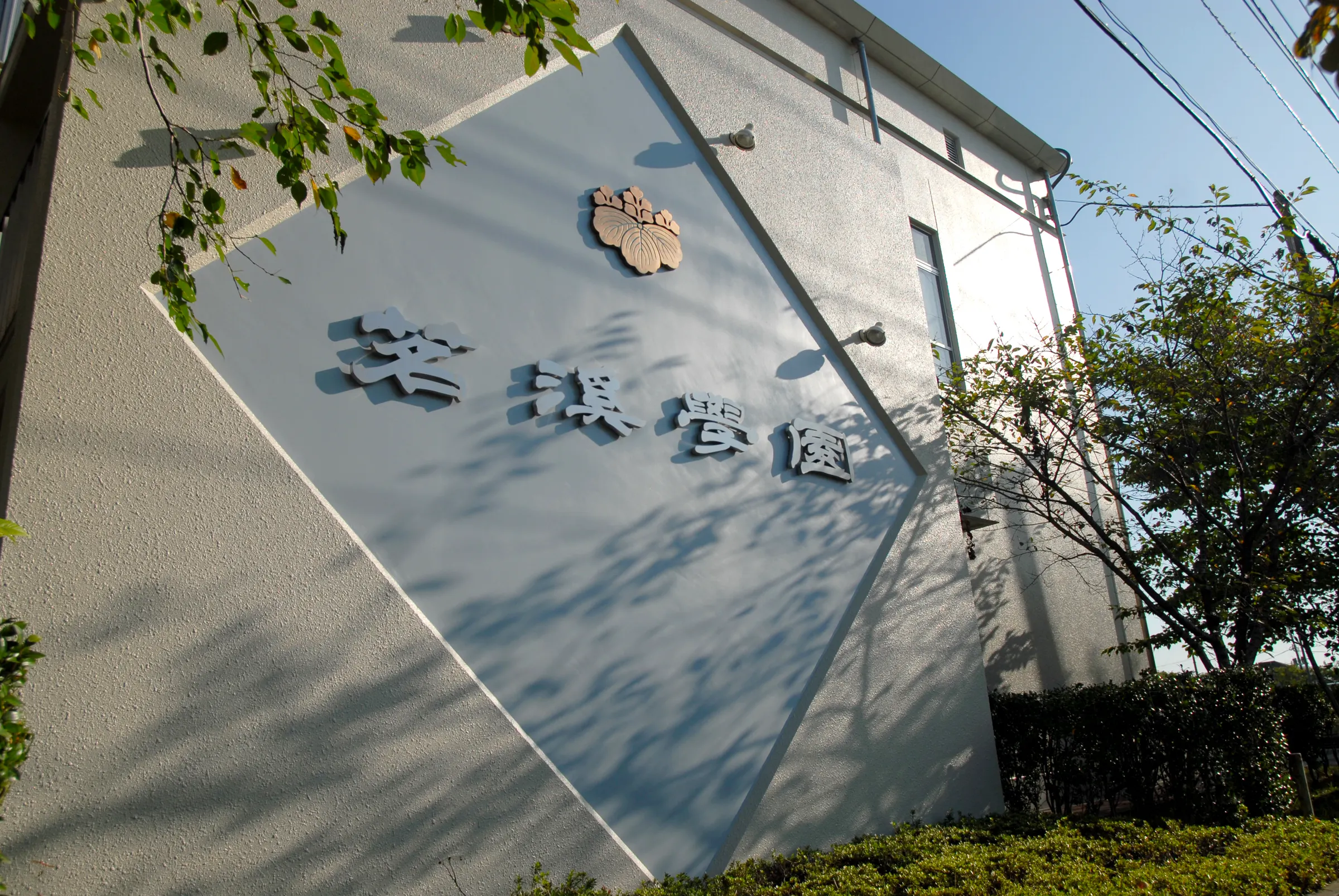 '茗溪學園' 교명판과 학교 문장이 붙은 교사동 벽