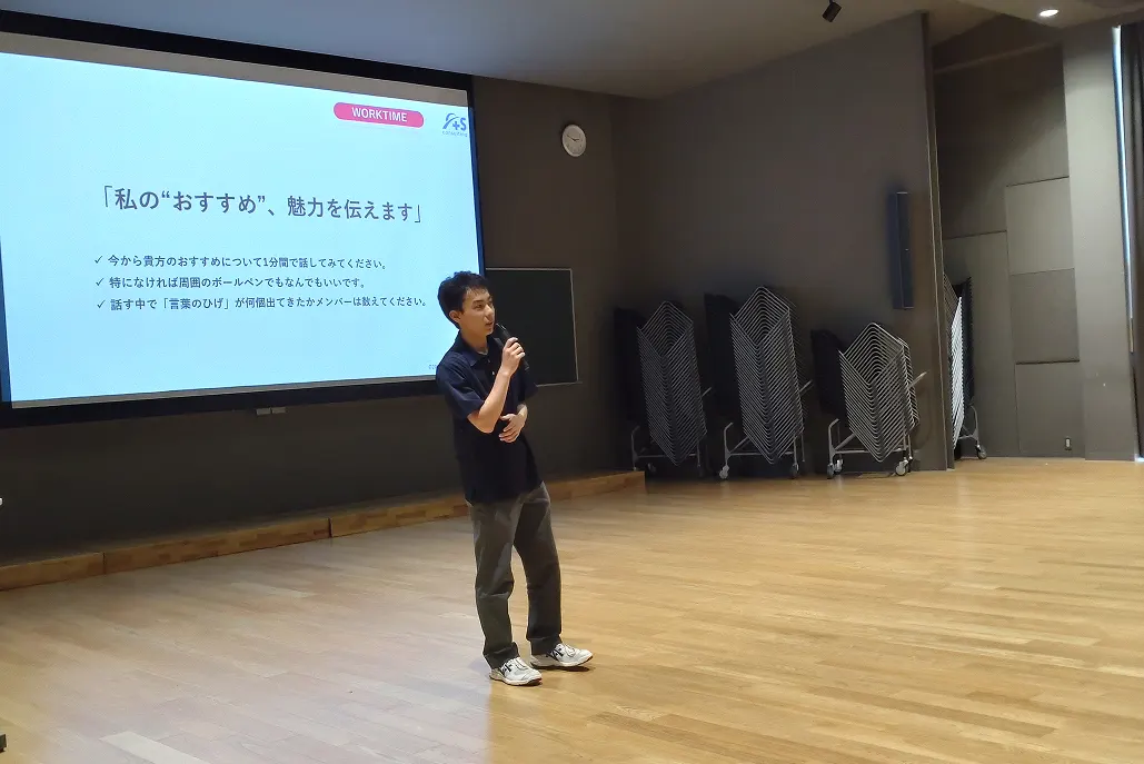 강당 무대에서 슬라이드를 띄워 놓고 발표하는 학생