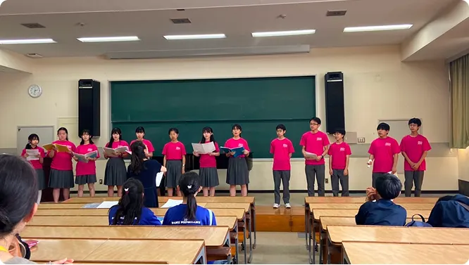 분홍 티셔츠를 맞춰 입고 교실에서 노래하는 합창부