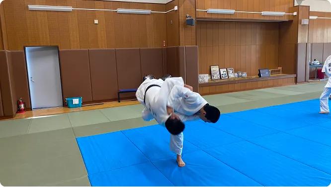 매트 위에서 메치기를 하는 유도부 학생